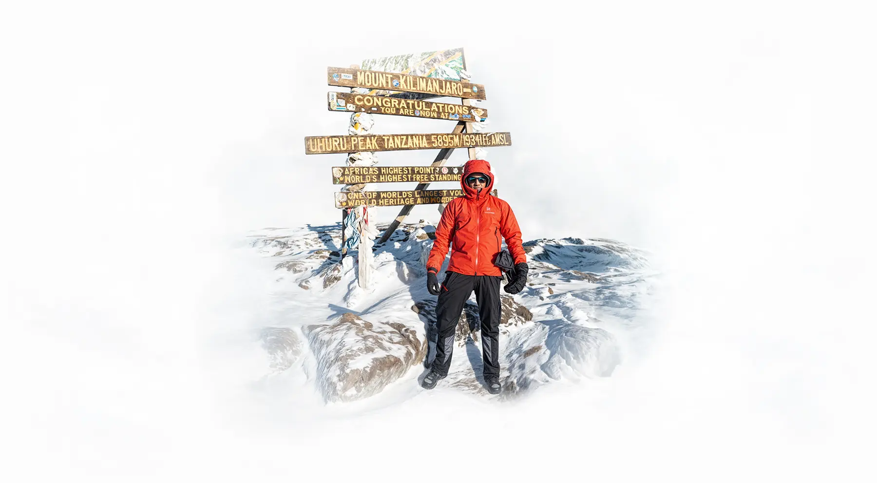 Bjergbestiger ved Uhuru Peak-skiltet på Kilimanjaro-bjergtoppen Bjergbestiger ved Uhuru Peak-skiltet på Kilimanjaro-bjergtoppen